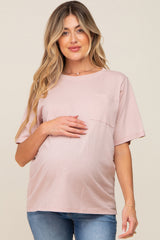 woman wearing a light pink maternity t-shirt with a pocket, gently holding her baby bump