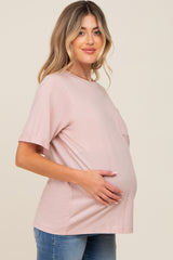 woman wearing a light pink maternity t-shirt and showing her baby bump while smiling