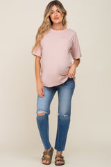 woman wearing a light pink short sleeve maternity top with a pocket and distressed denim jeans, showing her baby bump