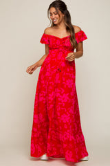 woman wearing a hot pink off-the-shoulder maternity dress with floral patterns and ruffle details, showcasing her baby bump