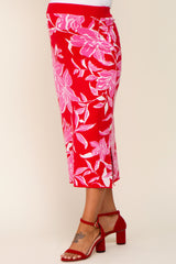 woman wearing a red floral maternity skirt with pink accents and a fitted style, standing in side profile