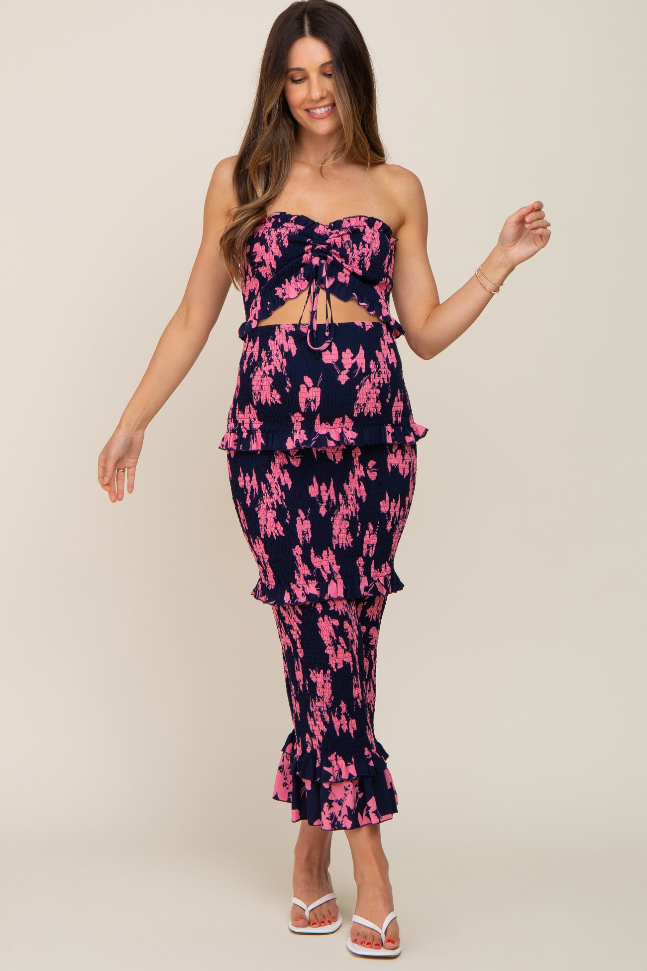 woman wearing a navy and pink floral smocked strapless top and matching tiered midi skirt