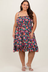 Plus size woman wearing a colorful floral smocked midi dress with spaghetti straps and white block heels