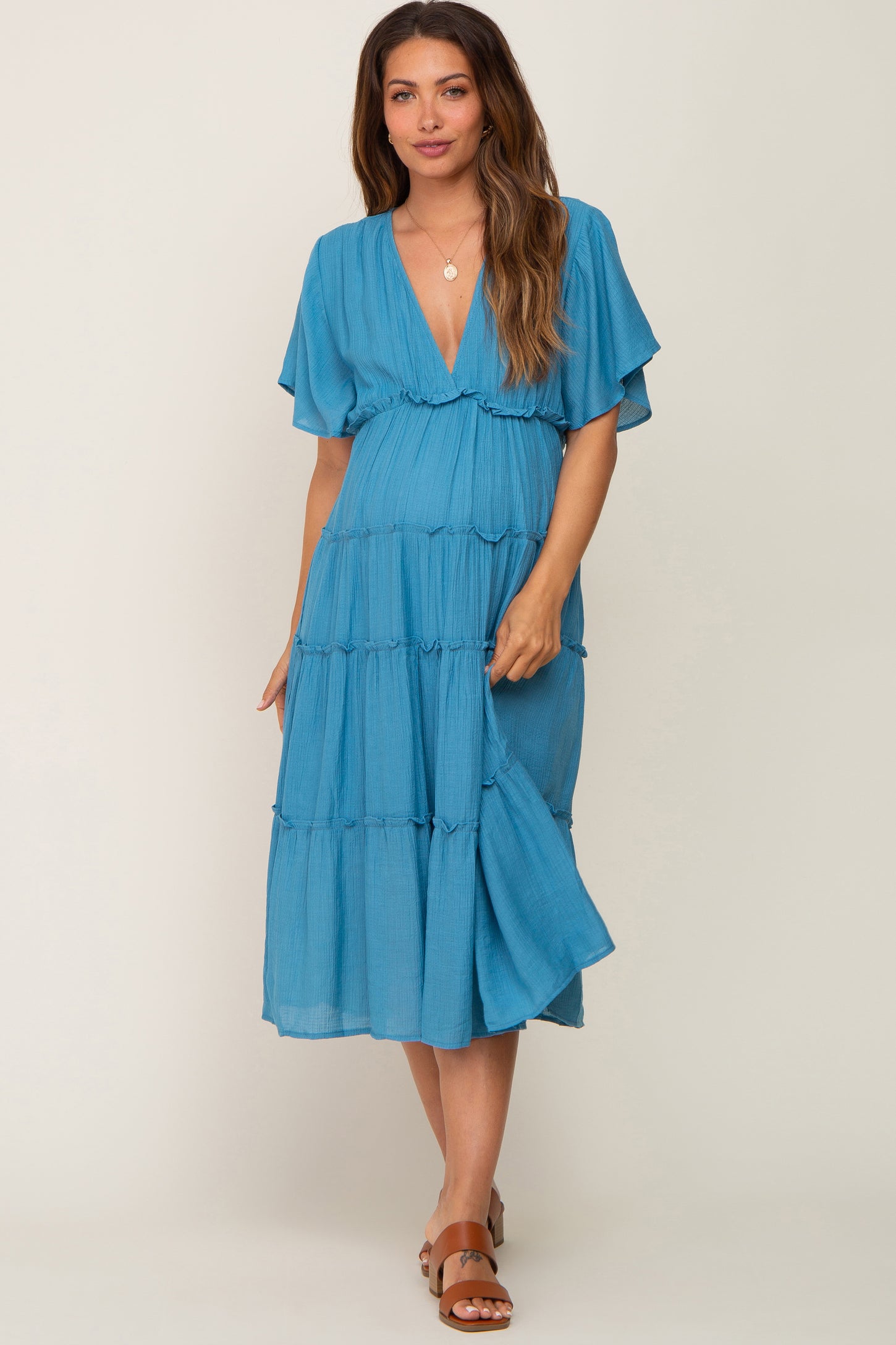 woman wearing a blue tiered maternity midi dress with short flutter sleeves and a v-neckline