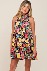 Woman wearing a sleeveless tiered mini dress with a vibrant floral print on a black background