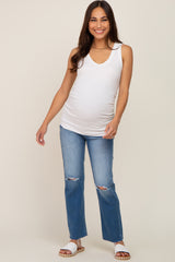 woman wearing a white maternity tank top and blue ripped flare jeans, showing her baby bump