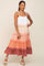 woman wearing a tiered colorblock maxi dress in white, peach, and mauve with white wedge sandals