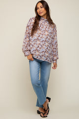 Woman wearing a floral high-neck long sleeve blouse and light wash straight leg jeans with black sandals