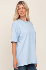 woman wearing light blue oversized t-shirt and silver chain necklace against a neutral background