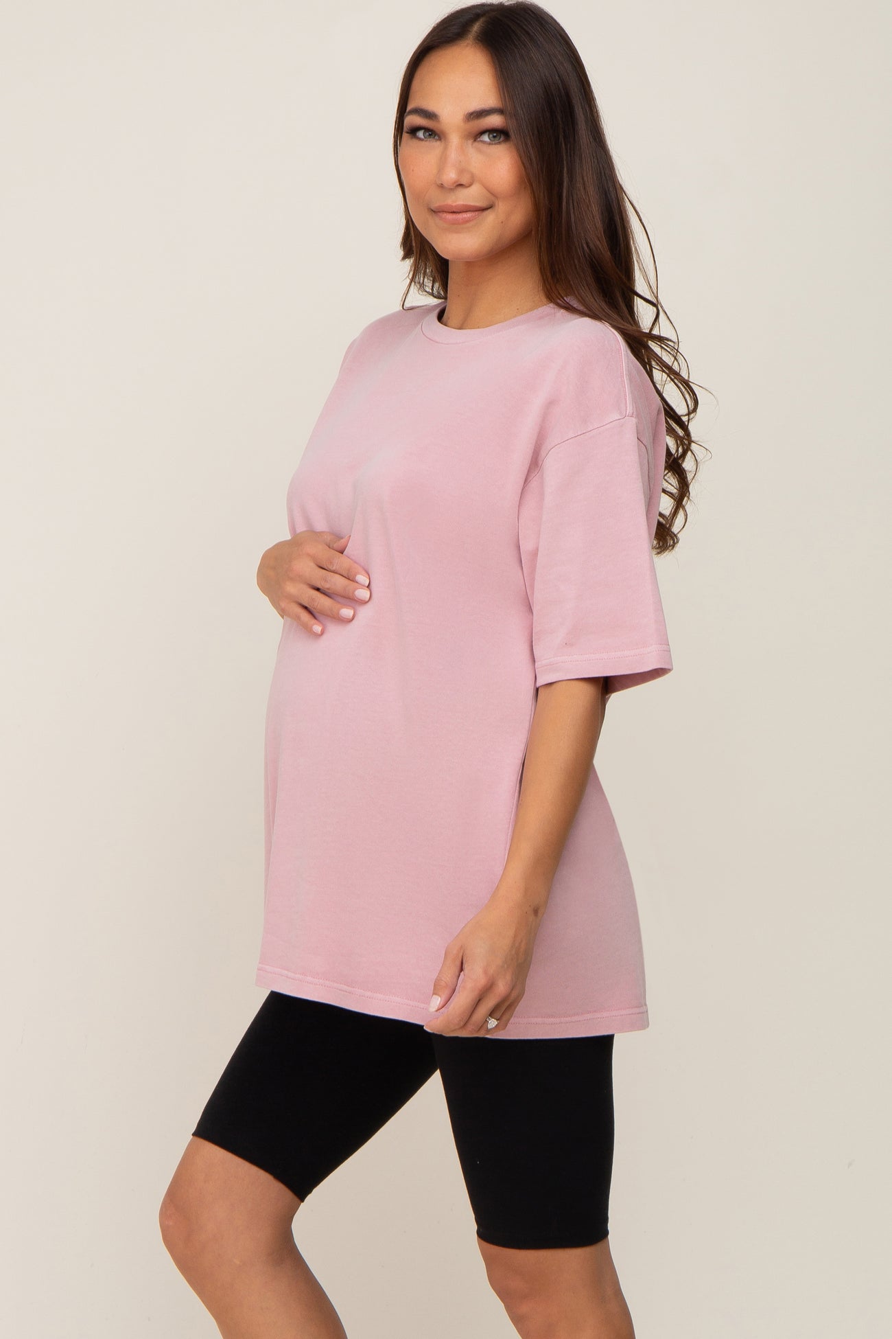 pregnant woman wearing a pink oversized maternity t-shirt and black biker shorts
