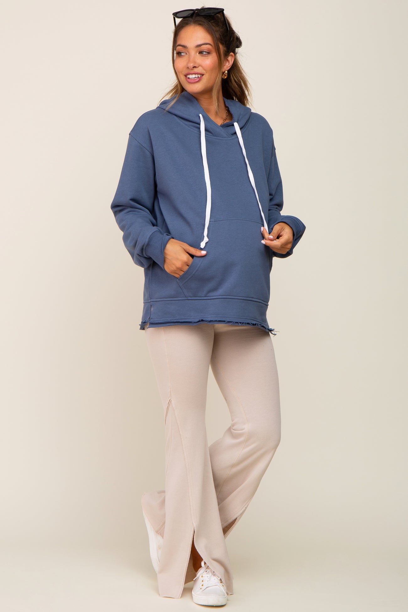 woman wearing a blue maternity hoodie and beige flare pants with side slits