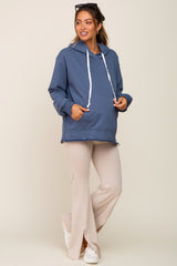 woman wearing a blue maternity hoodie and beige flare pants with side slits