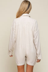 Back view of a woman wearing a beige linen long-sleeve romper with a collared neckline and button cuffs