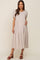 woman wearing a beige short sleeve tiered maternity midi dress with brown platform sandals