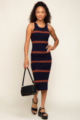 woman wearing a navy and brown striped midi dress holding a black leather handbag and wearing platform sandals