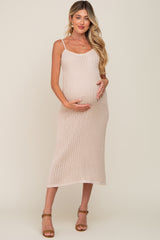 woman wearing a light pink ribbed maternity dress and gently cradling her baby bump