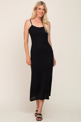 woman wearing a black ribbed midi dress with spaghetti straps and black sandals