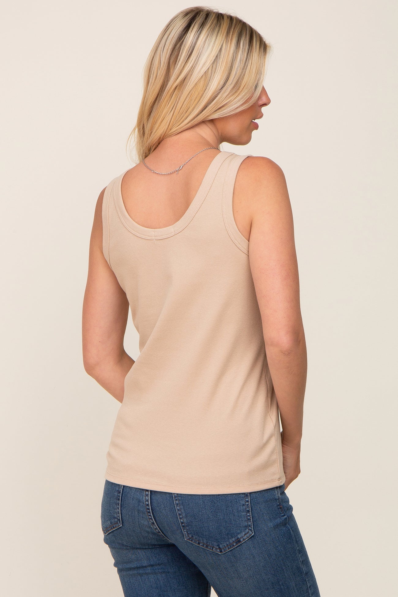 woman wearing a beige ribbed tank top, showing the back view, paired with blue jeans