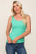 woman wearing a mint green ribbed tank top with a scoop neckline and denim jeans