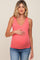 pregnant woman wearing a coral ribbed maternity tank top and blue jeans holding her baby bump