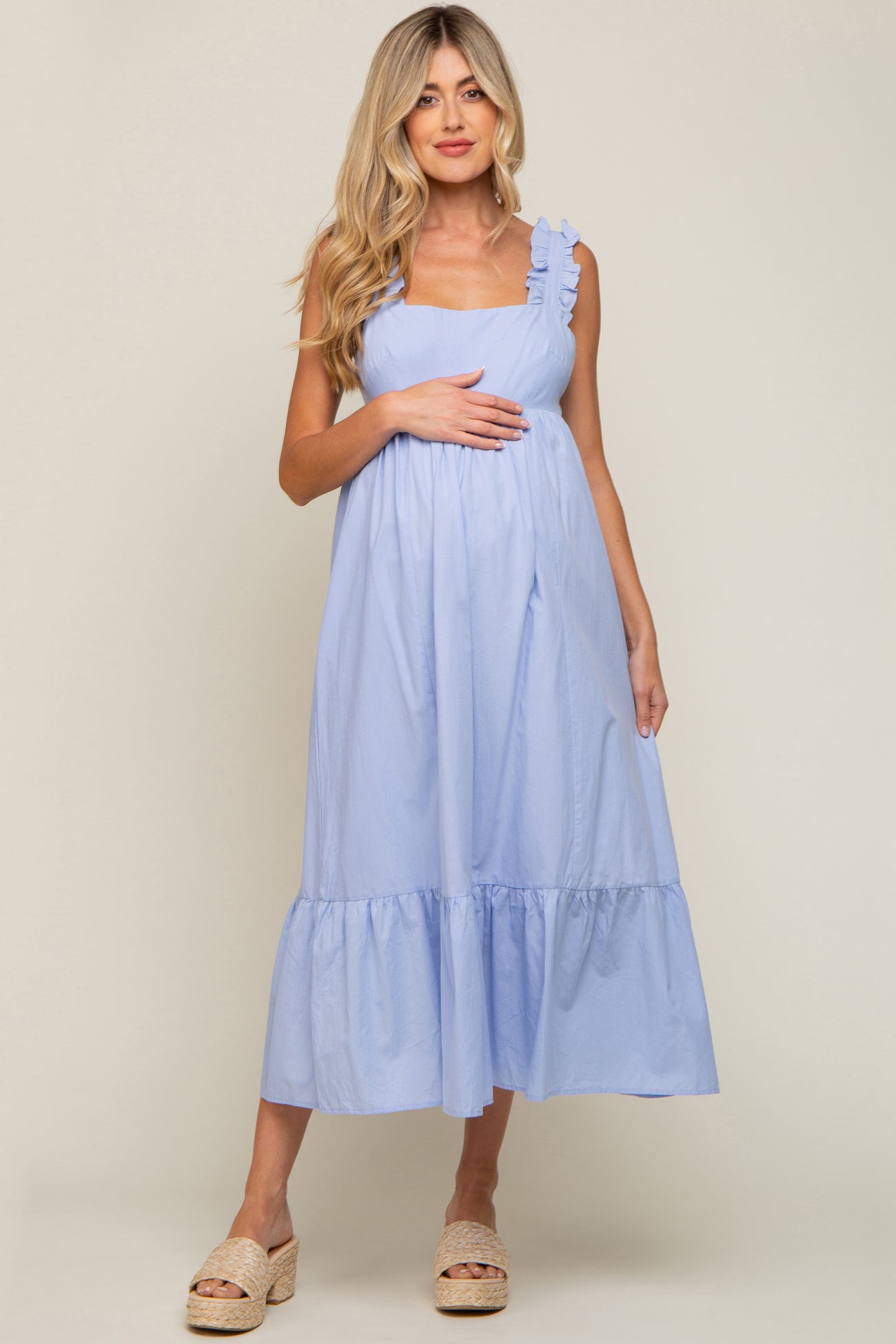 Pregnant woman in light blue sleeveless maternity midi dress with ruffle straps and tiered hem