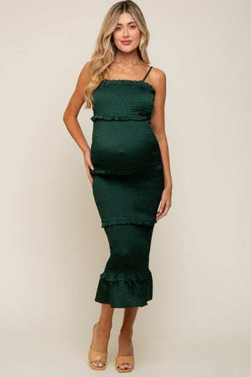 woman wearing a dark green maternity dress with ruffle details and a fitted silhouette, showing her baby bump