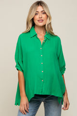 Woman wearing a green oversized button-down gauze shirt and blue jeans against a neutral background