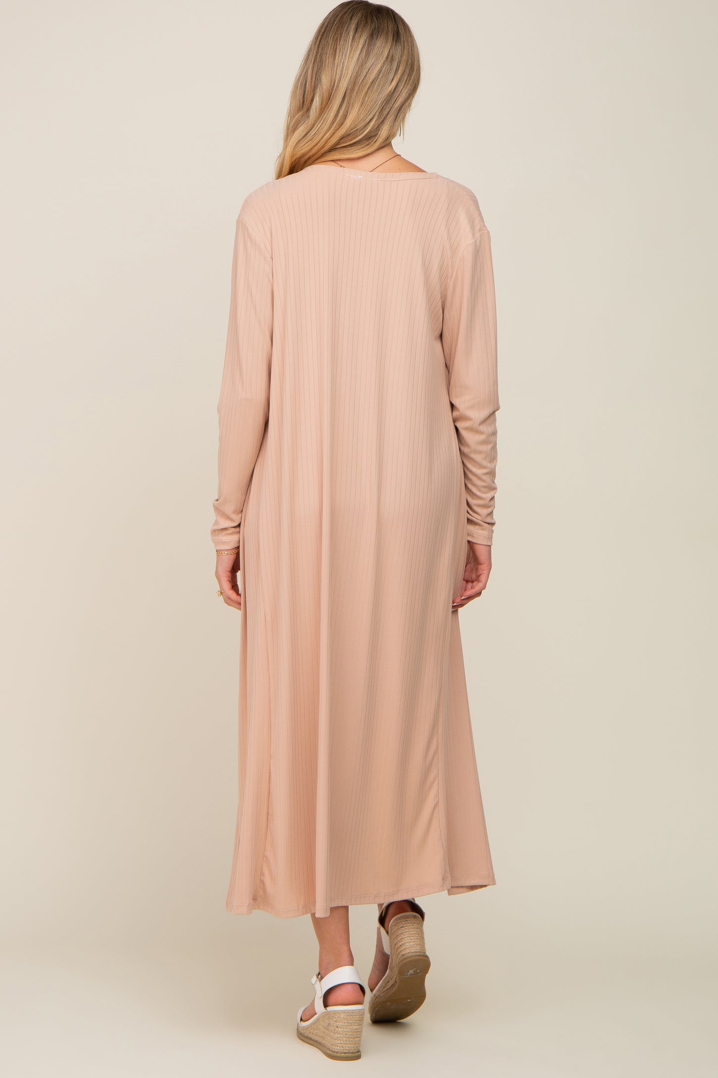 woman wearing a long blush pink maternity maxi dress with long sleeves seen from the back