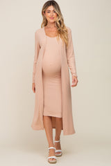 woman wearing a light peach maternity dress with a matching open-front cardigan and showing her baby bump