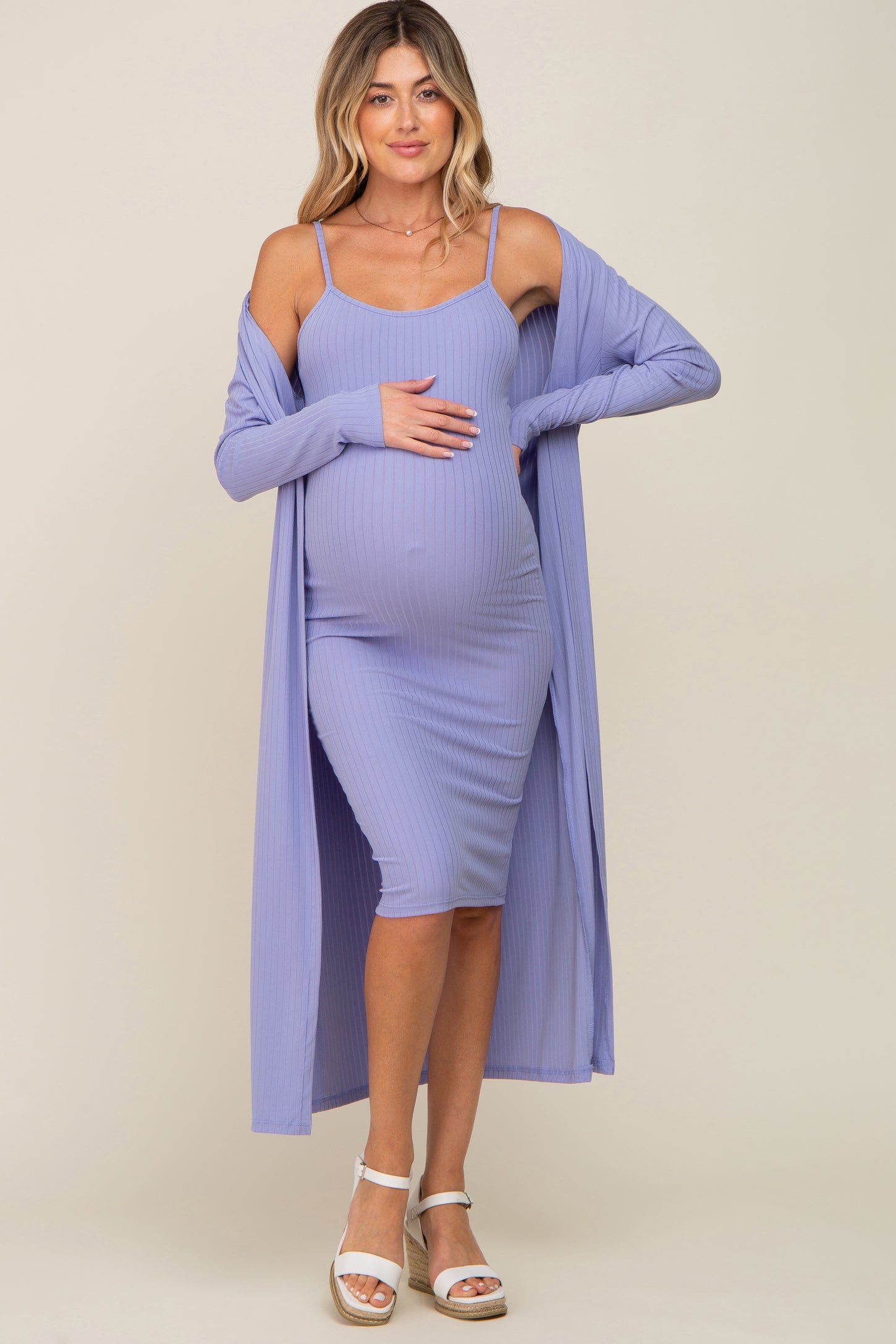 woman wearing a lavender ribbed maternity dress and long cardigan, holding her baby bump