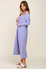 woman wearing a lavender ribbed midi dress with long sleeves and a side slit, posing with one hand on her hip