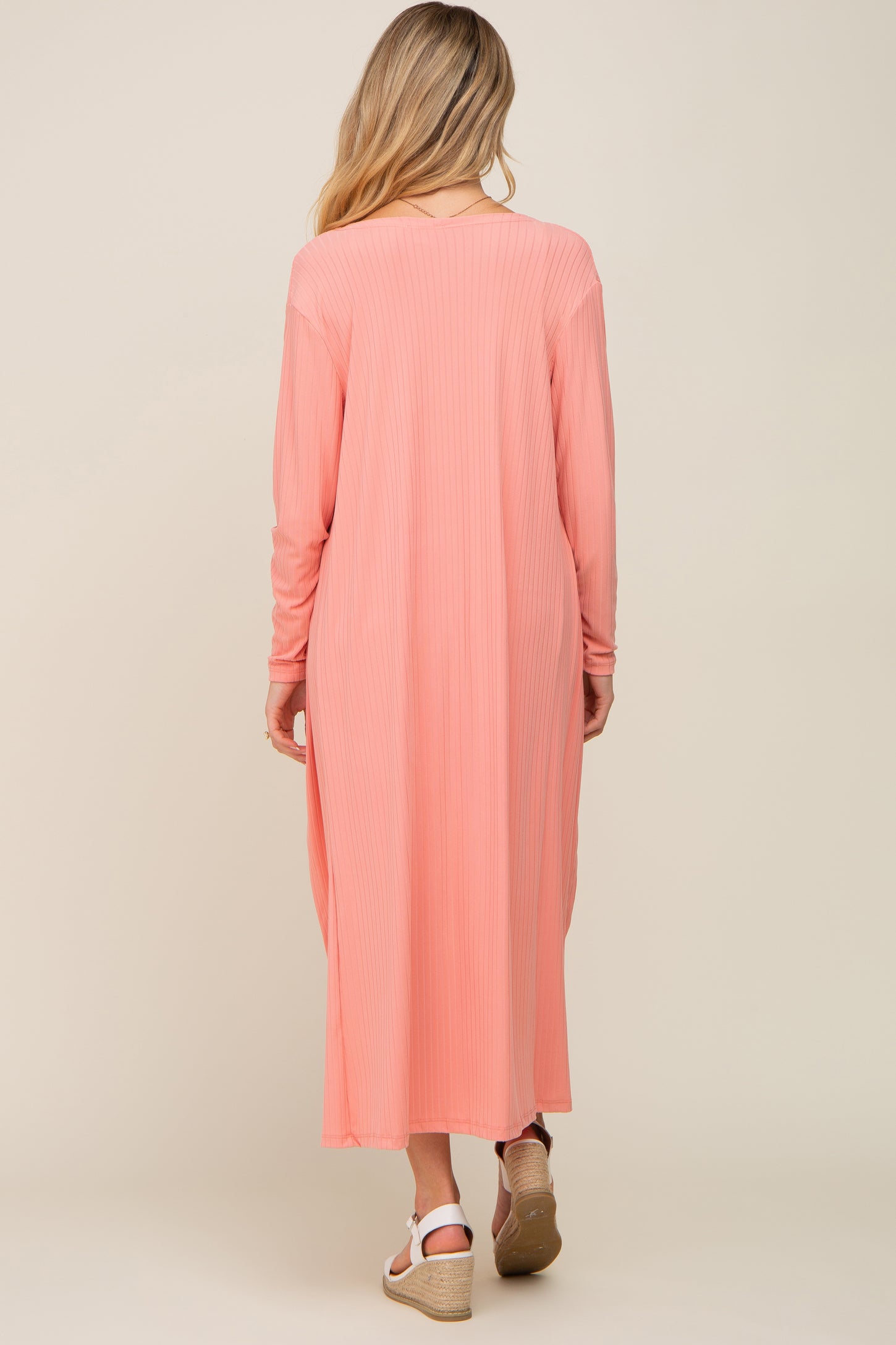 woman wearing a light pink long sleeve maternity dress with a ribbed texture, seen from the back