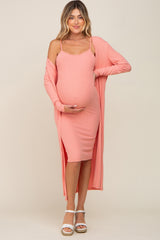 woman wearing a pink ribbed maternity dress with a matching cardigan, holding her baby bump