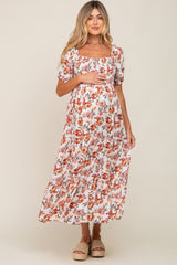woman wearing a white floral maternity maxi dress with square neckline and puff sleeves, holding her baby bump