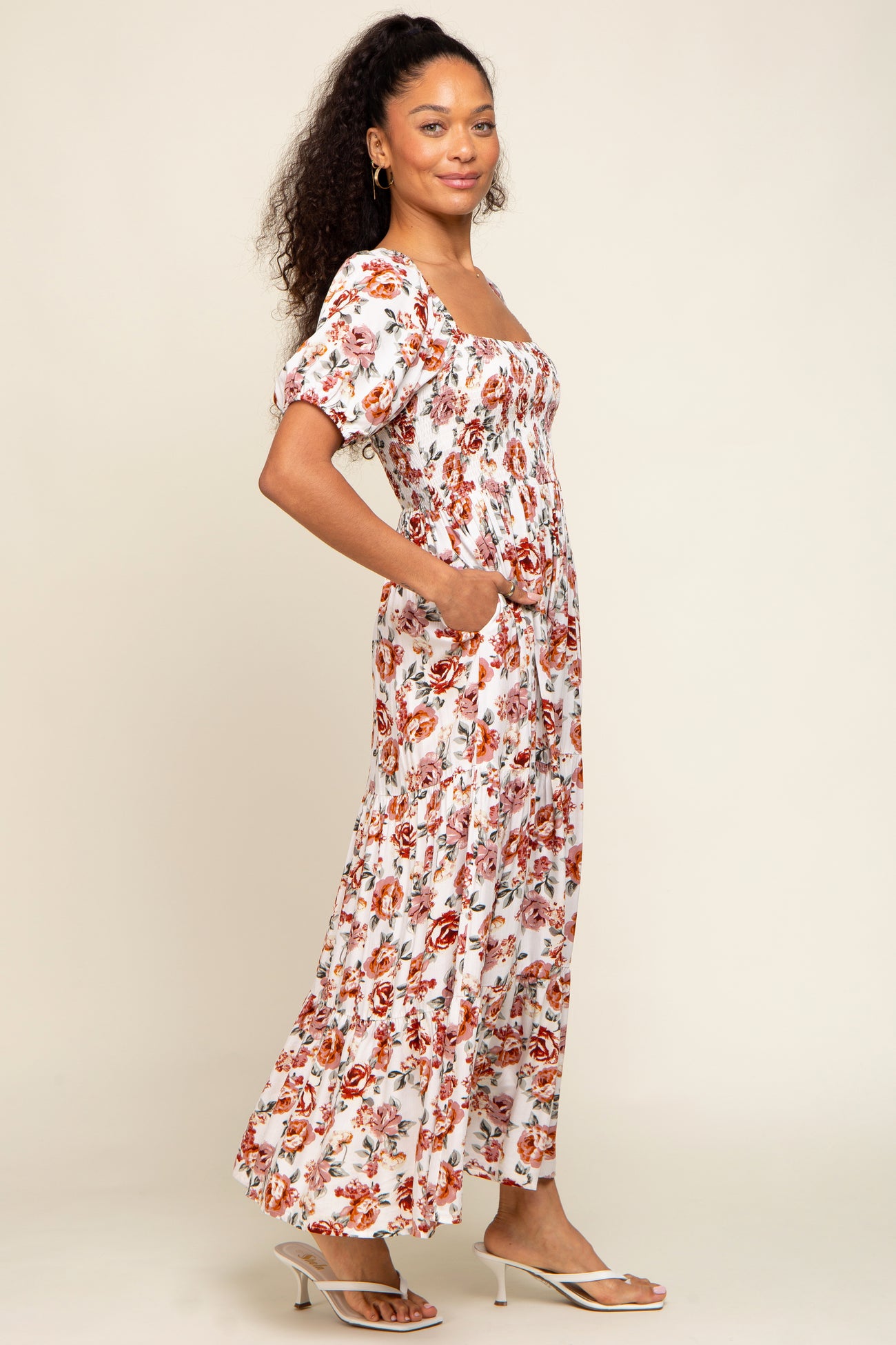 woman wearing a white floral maxi dress with puff sleeves and pockets, standing in a relaxed pose