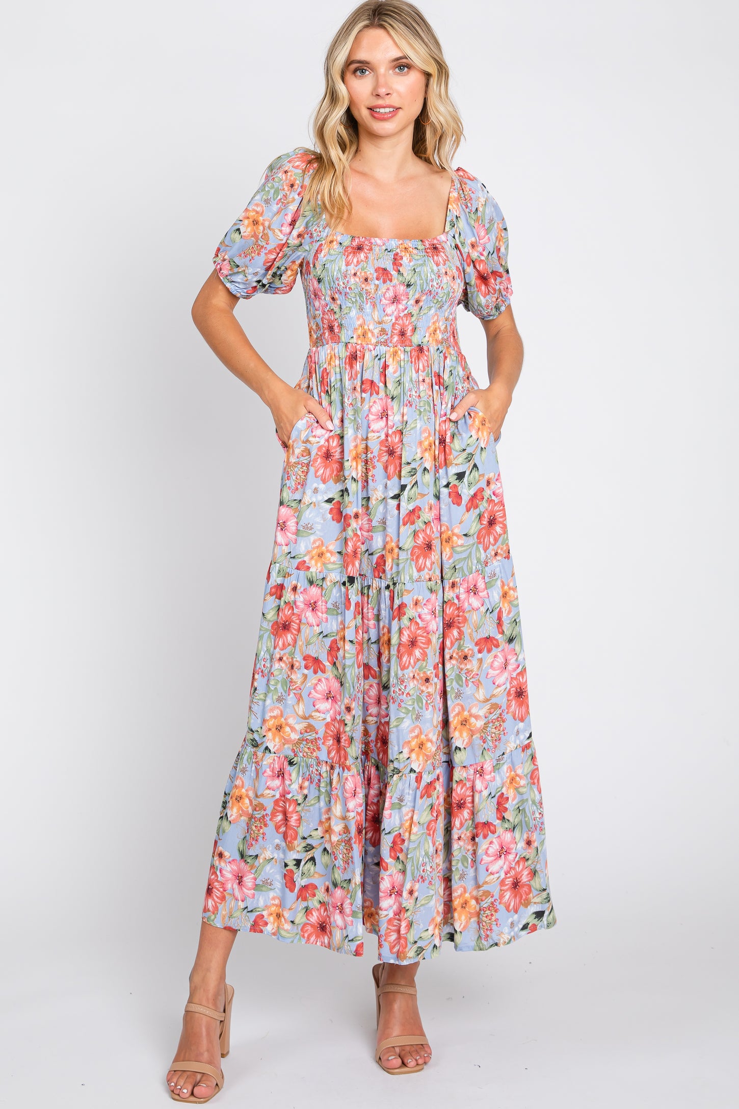 woman wearing a floral off-the-shoulder maxi dress with puff sleeves and pockets in a pastel color palette