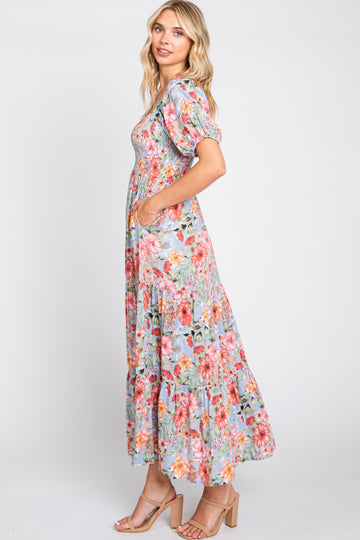 woman wearing a floral maxi dress with puff sleeves and a tiered skirt in pastel colors