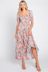 woman wearing a floral midi dress with puff sleeves and a smocked bodice, posed against a neutral background