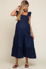 woman wearing a navy blue maternity dress with ruffled sleeves and a tiered skirt, showcasing a baby bump