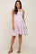 woman wearing a light purple tiered maternity dress with tie straps and brown block heel sandals