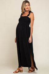Pregnant woman wearing a black smocked maternity maxi dress with tie straps and brown sandals