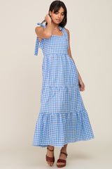 woman wearing a blue and white gingham tiered maxi dress with adjustable straps and a square neckline