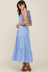 woman wearing a blue and white gingham maxi dress with tie straps and tiered skirt, styled with brown heeled sandals