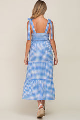 woman wearing a blue and white gingham maternity maxi dress with tie straps and a tiered skirt, showing her back