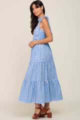 woman wearing a blue and white gingham maxi dress with ruffle tiers and a tied shoulder strap