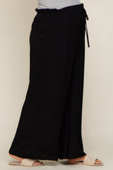 woman wearing black wide leg maternity pants with drawstring waist and woven sandals