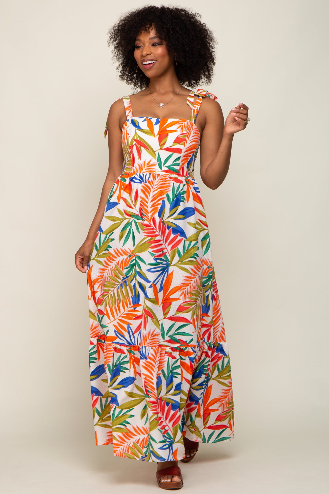 woman wearing a multicolored floral maxi dress with spaghetti straps and a tiered skirt