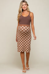 woman wearing a brown maternity tank top and a brown and beige checkerboard maternity skirt with a visible baby bump