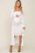 woman wearing a white maternity dress with a long cardigan, holding her baby bump