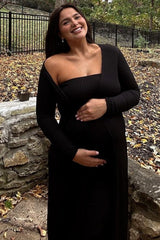 woman wearing a black ribbed off-the-shoulder maternity dress and holding her baby bump